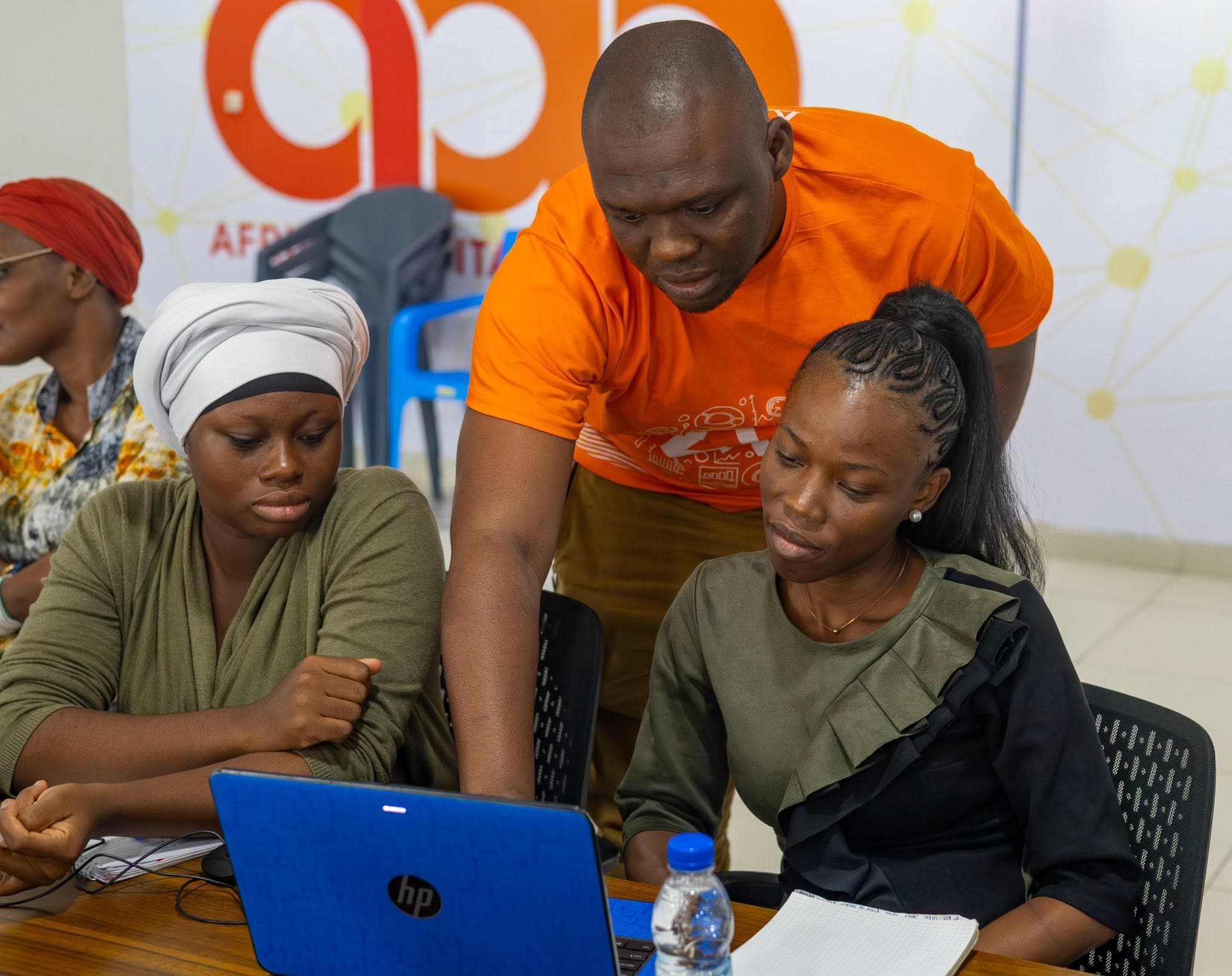 Abdoul Karim Camara accompagne deux participantes de She Is The Code dans un exercice sur ordinateur